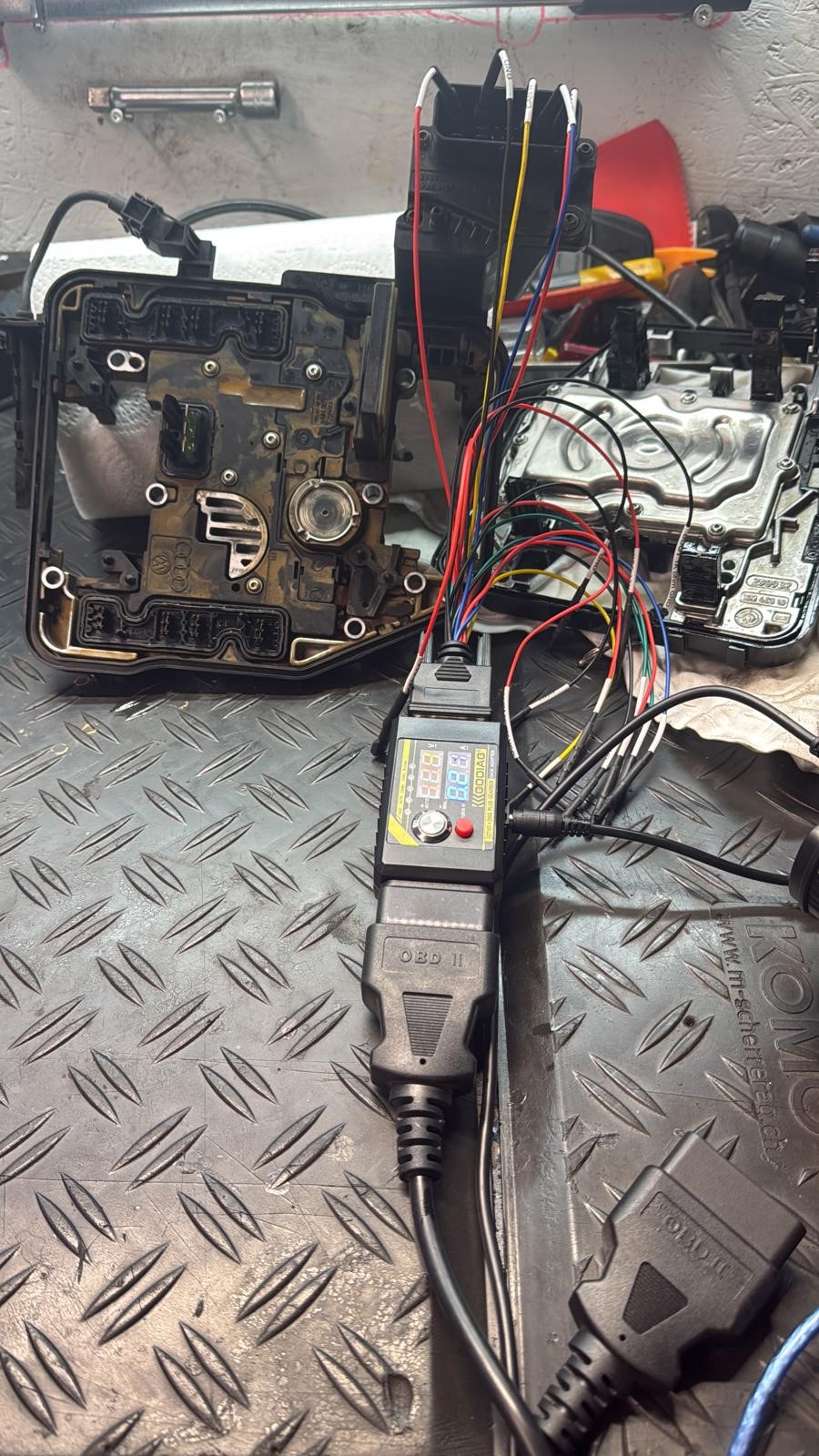Fahrzeugmodule mit angeschlossenen Leitungen und Programmiergerät auf einer Werkbank